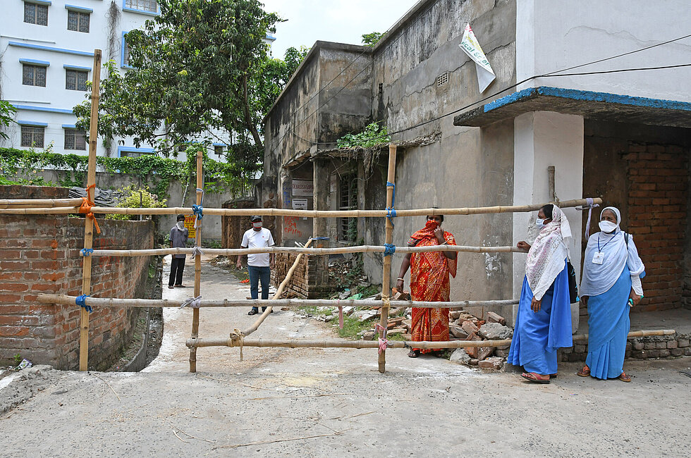 Two female government health workers standing across a containment zone during COVID-19 pandemic